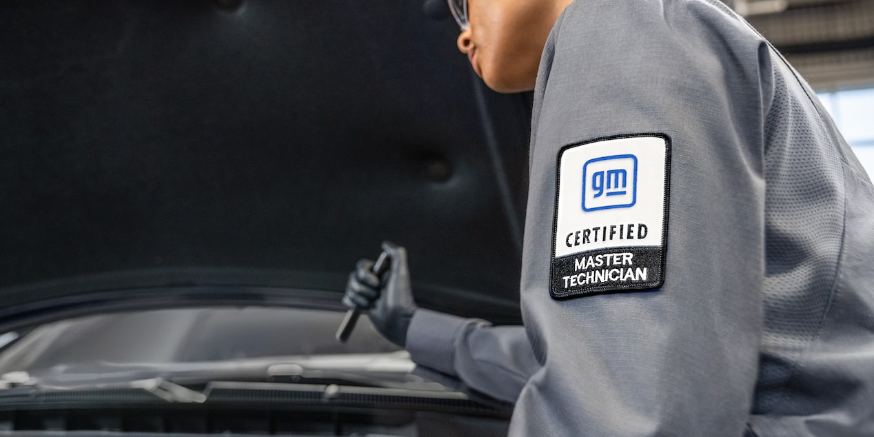 Buick Certified Service Technician Inspecting Vehicle's Engine Bay With a Flashlight