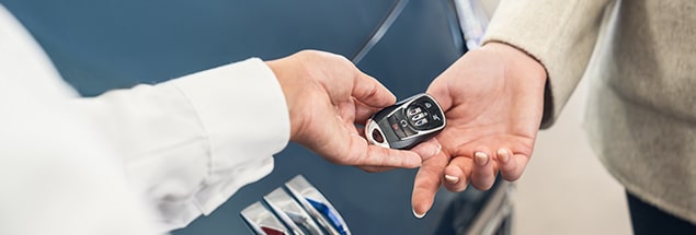 Man and Woman Exchanging Key Fob Next to Black Buick Vehicle