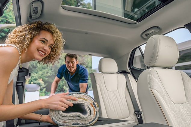 Man and Woman Holding a Rolled Up Rug Inside a White Interior Vehicle